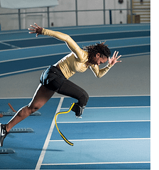 Femita begins a race, wearing a yellow shirt and black running shorts. Her arms are in a running motion, and she has a prosthesis on her right leg. 